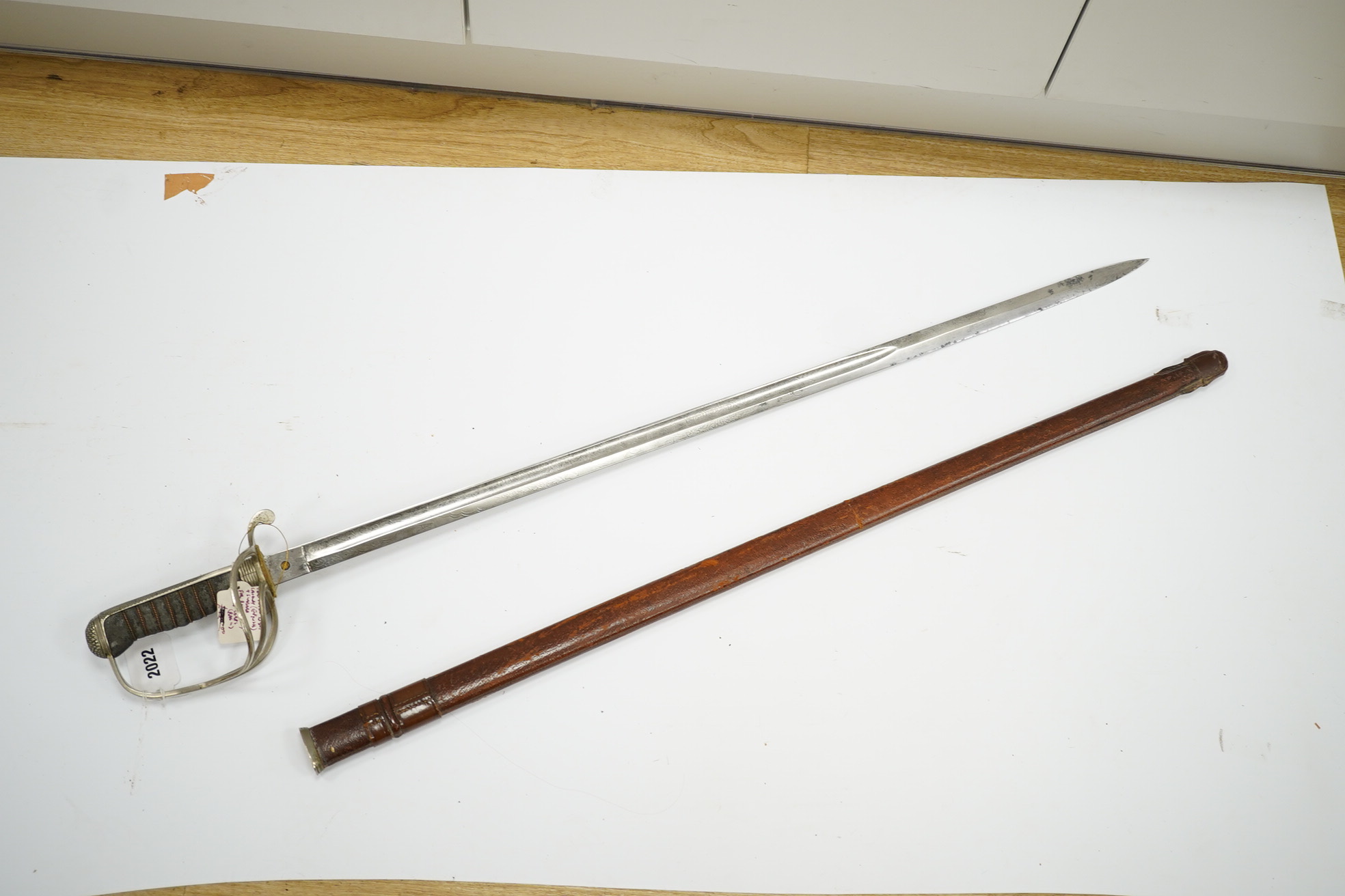 An 1821 pattern GVIR light cavalry officer’s sword in its leather scabbard, Royal Army Service Corps, blade etched with owners initials; JNDA and also with initials RASC, with regulation nickel guard, in its leather fiel